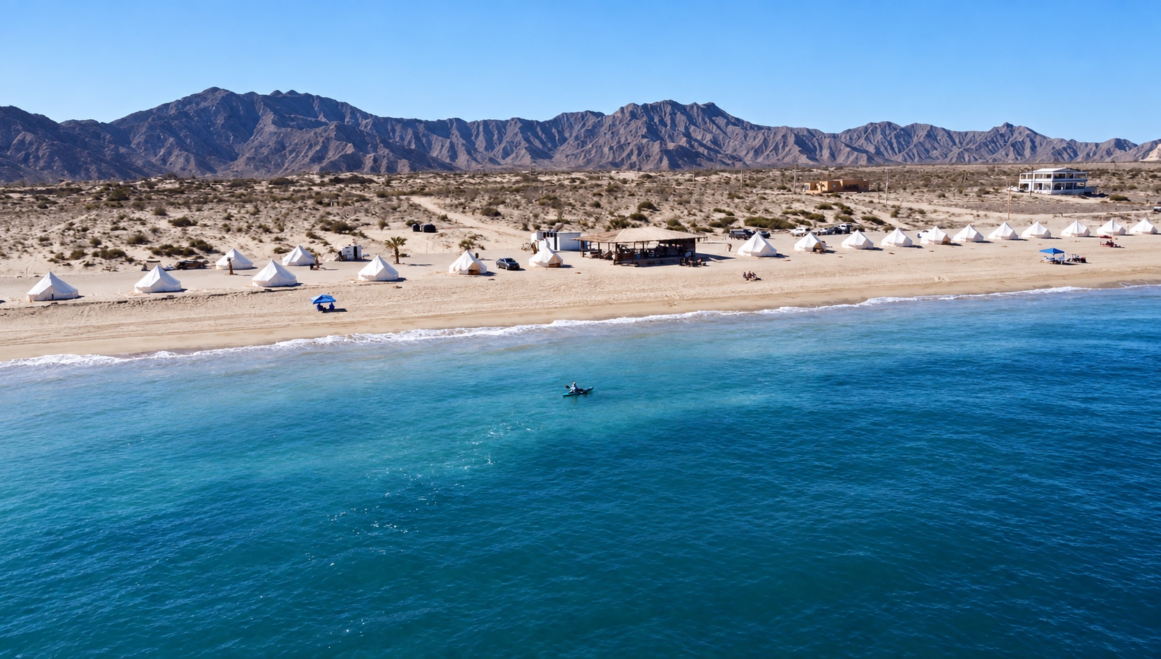 White glamping tents between Baja’s desert mountains and the blue Sea of Cortez